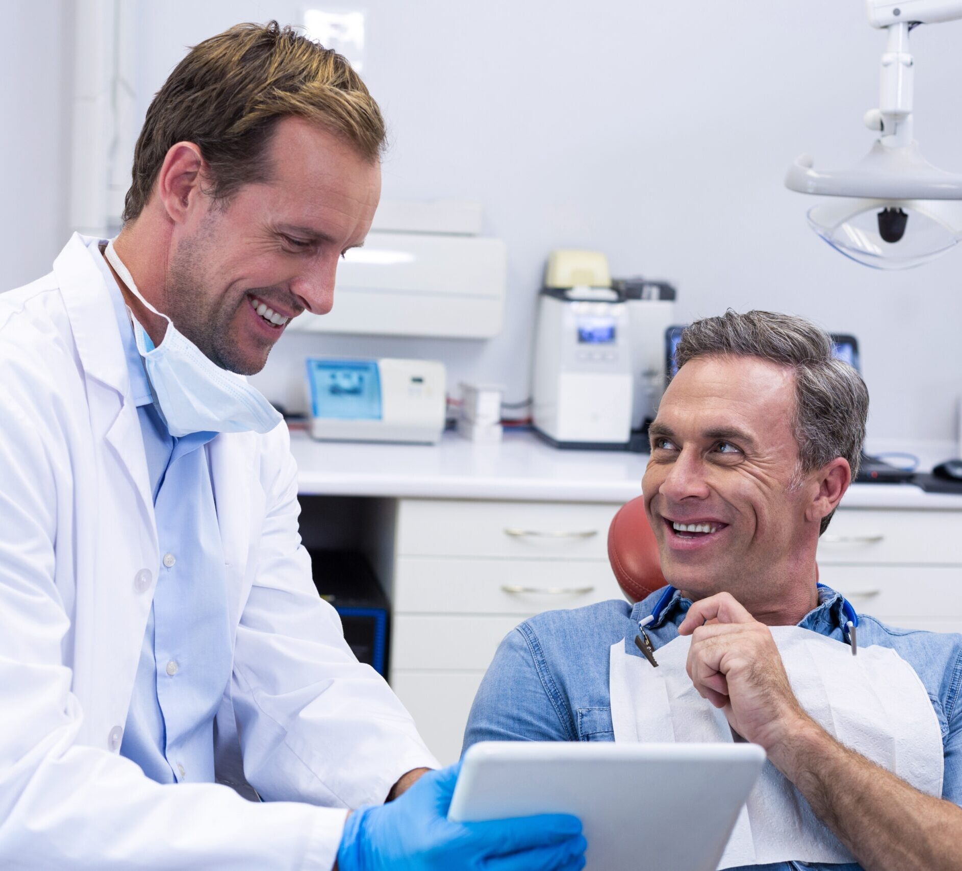 Dentist discussing over digital tablet with male patient