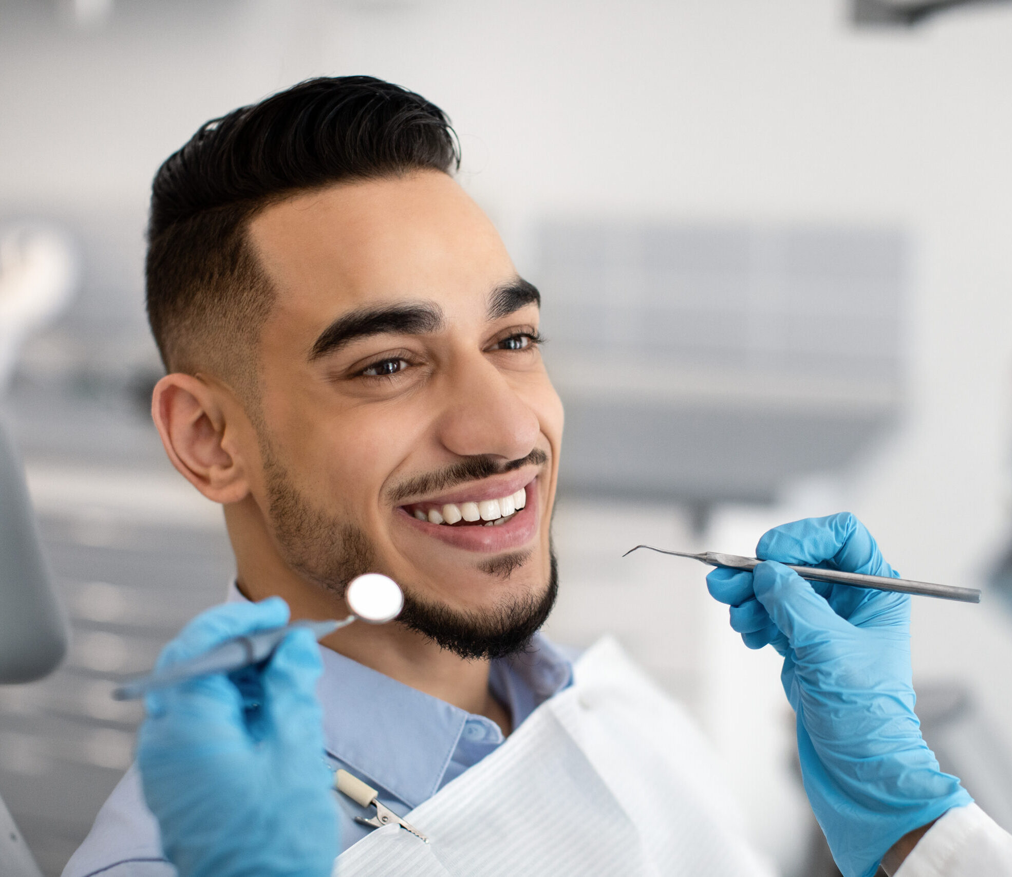 Closeup Of Happy Middle Eastern Male Patient Getting Dental Treatment In Modern Clinic, Islamic Dentist Woman Examining Teeth Of Arab Man With Sterile Tools In Stomatological Cabinet, Cropped Shot