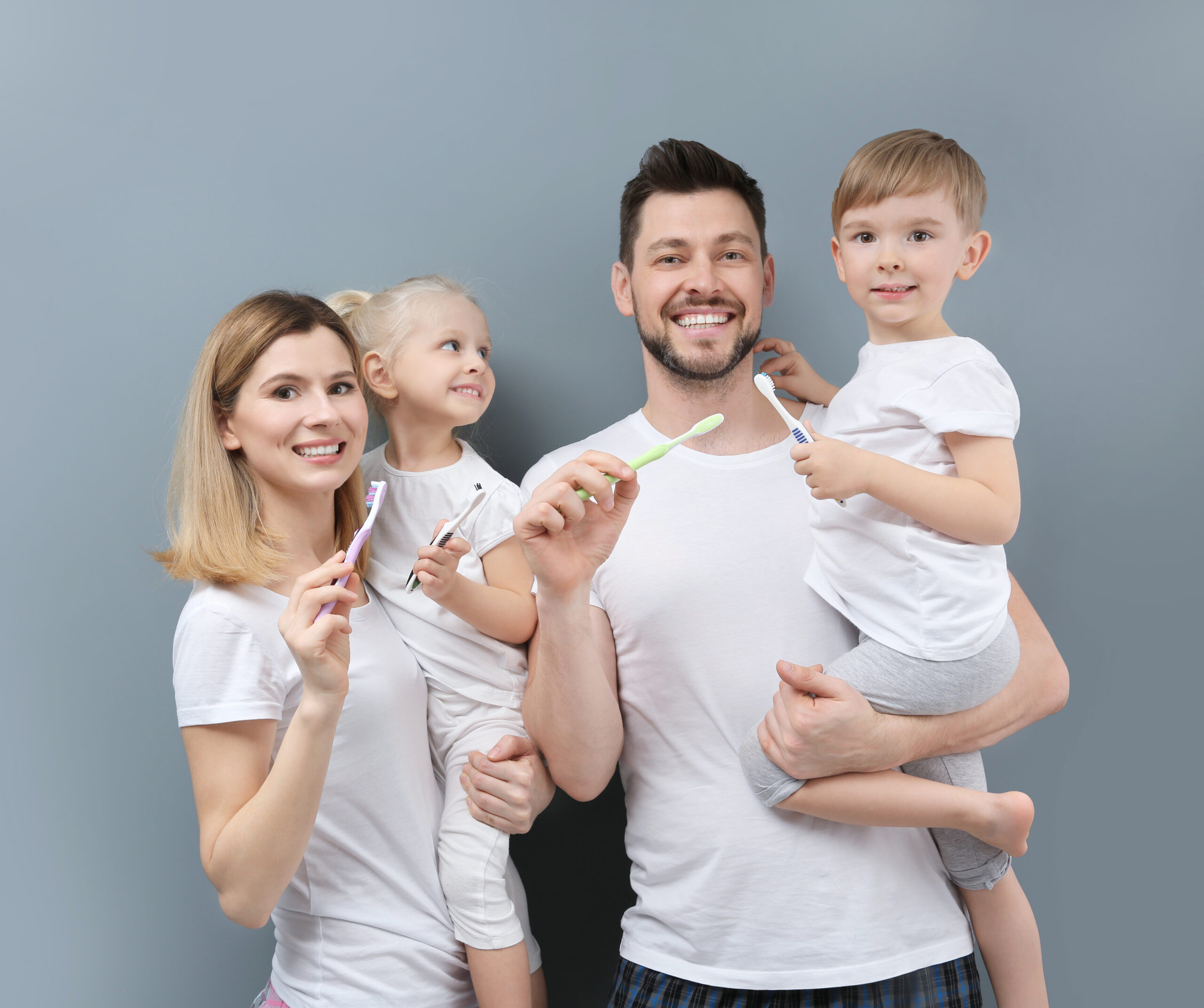 family brushing teeth on grey background