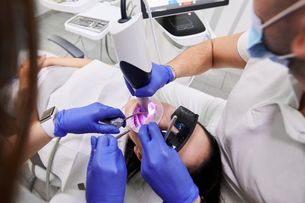 Dentist and assistant using an intraoral scanner to examine a patient's teeth