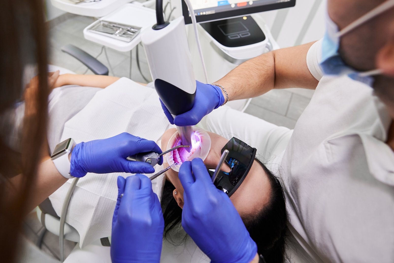 Dentist and assistant using an intraoral scanner to examine a patient's teeth