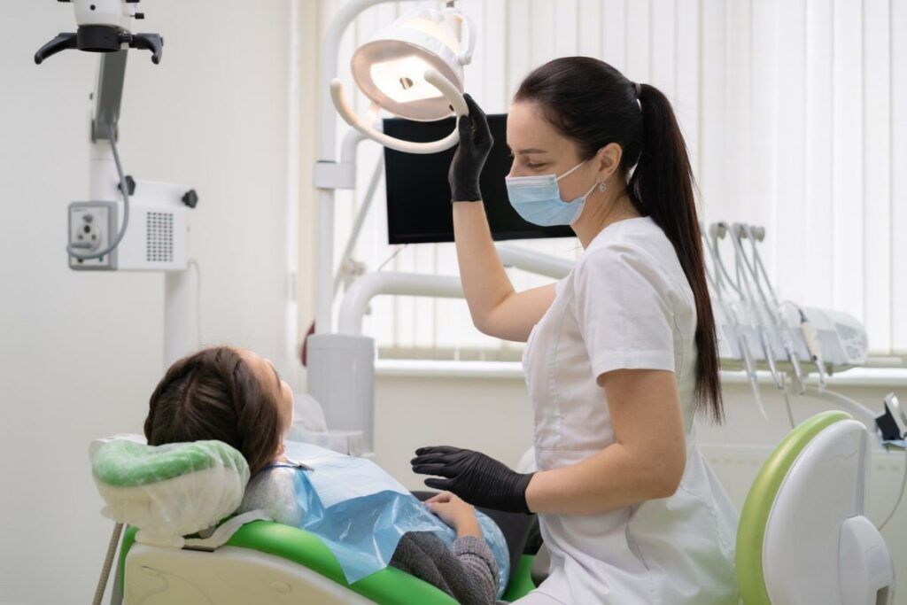 Caucasian woman dentist doctor in office with dental equipment microscope treats teeth to patient in chair. Place for your text.